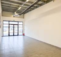 Tágas üzlethelyiségek járólappal és nagy ajtókkal.