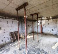 Egy kunyhó belső tere ideiglenes támaszokkal, fedetlen téglákkal és építőanyaggal.