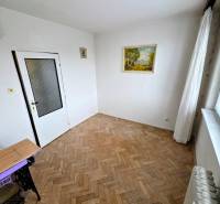Szoba egy háromszobás lakásban fa dekorációjú padlóval és egy képpel a falon.