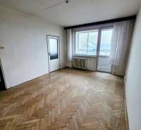 Egy háromszobás lakás egy helyisége, fa hatású padlóval és nagy ablakokkal.