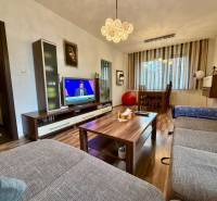 Nappali egy háromszobás lakásban, fa mintázatú padlóval és kényelmes kanapéval.