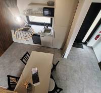 A kunyha belső tere étkezőasztallal, konyhapulttal és fa padlóburkolattal.