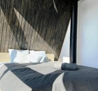 Ágy csíkos takaróval és faház falakkal.