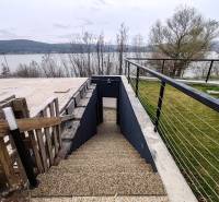 Külső tér Holčíkovce-ban az Eva utcán, kilátással a tóra és lépcsővel.