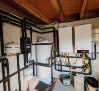 Fűtési technikai berendezés családi házban összekapcsolt csövekkel és bojlerrel.