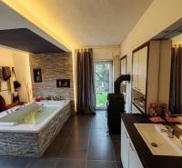 Tágas fürdőszoba káddal és csempékkel egy családi házban, fa dekorációjú padlóval.