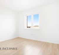 Üres szoba világos falakkal és fa dekorációjú padlóval egy háromszobás lakásban.