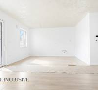 Tágas szoba fa mintázatú padlóval és nagy ablakokkal egy háromszobás lakásban.