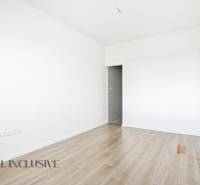 Szoba egy háromszobás lakásban fehér falakkal és fa dekorációjú padlóval.