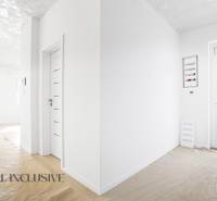 Világos folyosó egy háromszobás lakásban fehér falakkal és fa dekorációjú padlóval.