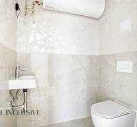 Fürdőszoba WC-vel és mosdóval egy háromszobás lakásban, világos csempe, víztartály.