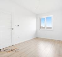 Szoba egy háromszobás lakásban fehér falakkal és fa dekorációjú padlóval.