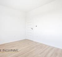 Üres szoba fehér falakkal és fa dekorációjú padlóval egy háromszobás lakásban.