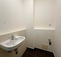 WC a négy szobás lakásban fehér mosdóval és fekete csempével.