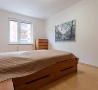 Hálószoba egy kétszobás lakásban beépített ággyal és képpel a falon.