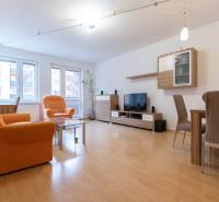 Nappali egy kétszobás lakásban narancssárga fotelekkel és fa mintázatú padlóval.