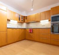 Két szobás lakás konyhája fa mintás padlóval és beépített készülékekkel.