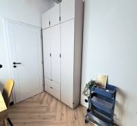 Stílusos sarok egy háromszobás lakásban, fa hatású padlóval és tároló polccal.