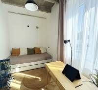 Szoba egy háromszobás lakásban fa dekorációval, ággyal és íróasztallal, amelyen egy tablet található.