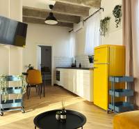 3 szobás lakás belső tere fa mintás padlóval, sárga hűtőszekrénnyel és fehér konyhabútorral.