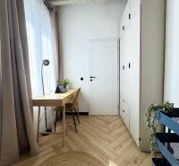 A 3 szobás lakásban a padló, az íróasztal és a magas fehér szekrény fa dekorációja dominál.