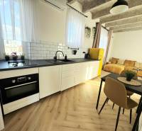 Konyha fehér szekrényekkel, színes hűtőszekrénnyel és fa dekoros padlóval.