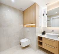 Fürdőszoba fa dekoros padlóval egy kétszobás lakásban, világos csempék és függesztett WC.