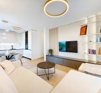 Nappali egy kétszobás lakásban kanapéval, konyhával és fa dekoros padlóval.