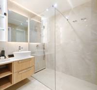 Fürdőszoba egy kétszobás lakásban nagy tükörrel és üveg zuhanykabinnal.