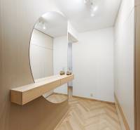 Előszoba fa mintázatú padlóval és nagy tükörrel egy kétszobás lakásban.