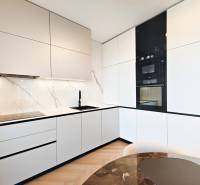 Konyha egy kétszobás lakásban fehér szekrényekkel és fa dekoros padlóval.