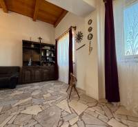 Belső tér egy kőpadlós és fagerendás mennyezetű házikóban.