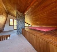 A faház padlása fa dekorációval és kő kéménnyel emlékeztet egy hangulatos pihenőhelyre.