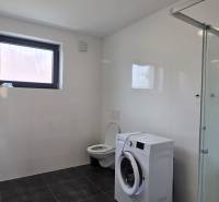 Fürdőszoba zuhanyzóval, mosdóval és mosógéppel egy háromszobás lakásban.