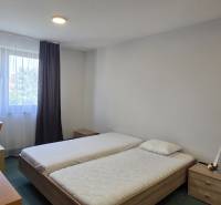 Hálószoba két ággyal, íróasztallal és ablakkal egy háromszobás lakásban.