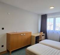 Hálószoba ágyakkal és bútorokkal egy háromszobás lakásban, fehér falak, fa dekor padló.