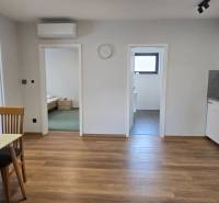 Konyha egy 3 szobás lakásban fa mintázatú padlóval és étkezőasztallal.