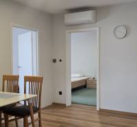 Étkezőasztal székekkel és fa dekorációjú padló a háromszobás lakásban.