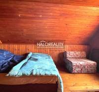 Tetőtéri szoba faházzal, faburkolattal és két ággyal.