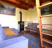 A ház belseje kandallóval, fa mennyezettel és lépcsővel a tetőtérbe.