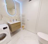 Fürdőszoba egy egyszobás lakásban mosógéppel, mosdóval és kerámia burkolatokkal.