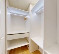 Beépített szekrény világos belső térrel és fa dekoros padlóval egy egyszobás lakásban.