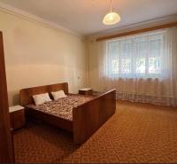 Ágy fotellel és éjjeliszekrényekkel a hálószobában, szőnyeggel.