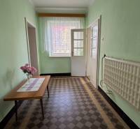 Egy családi ház folyosója, asztalon virágokkal és csempézett padlóval.