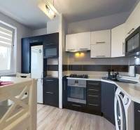 Konyha egy 3 szobás lakásban, konyhabútorral és háztartási gépekkel, fa hatású padlóval.