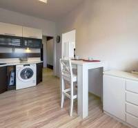 Konyha egy háromszobás lakásban étkezőasztallal és fa dekorációjú padlóval.