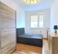 Világos hálószoba egy háromszobás lakásban, fa dekoros padlóval és nagy szekrénnyel.