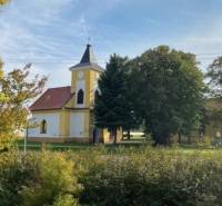 Egy templom zölddel körülvéve Práznovce mezőgazdasági és erdészeti területein.