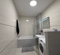 Fürdőszoba egy kétszobás lakásban zuhanyzóval, káddal és mosógéppel.