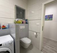 Fürdőszoba mosógéppel, WC-vel és csempével egy kétszobás lakásban.